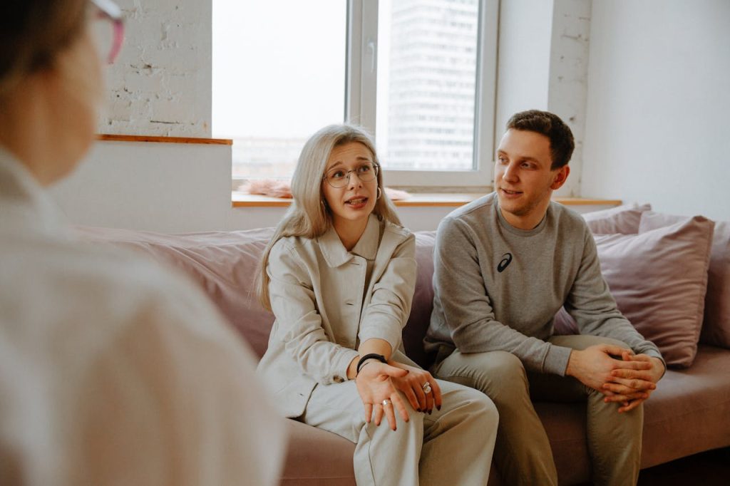 couple-talking-with-therapist-3958379 A couple and therapist engaged in a discussion during a therapy session indoors.