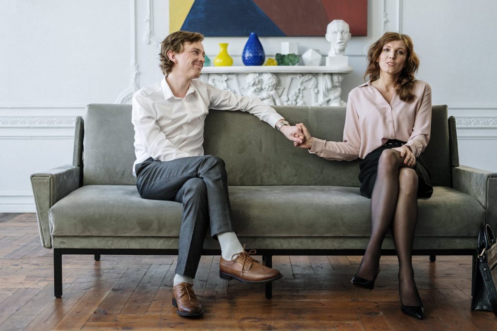 woman-in-white-long-sleeve-shirt-sitting-on-gray-couch-4098218 A couple in a therapy session holding hands, conveying support and connection.